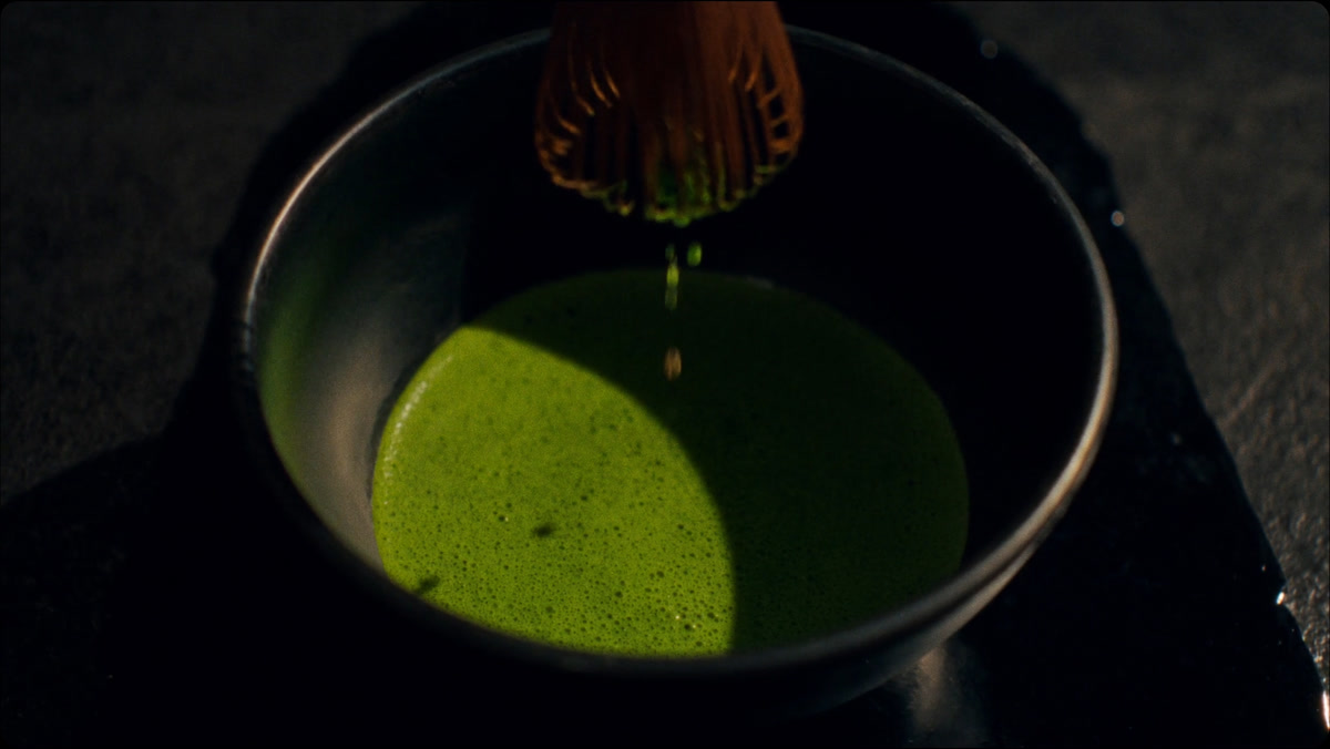Matcha recién batido en un tazón negro, con el batidor de bambú levantándose